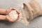 Female hands with heap of raw rice on textured background