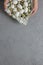 Female hands hold chicken and quail eggs in a plate with a towel on a gray concrete background. Top view. Flat lay