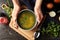 Female hands hold chicken soup or broth on a wooden table