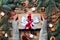 Female hands hold Gift box with bow. Christmas tree and decorations, cane caramel and oranges nuts Wooden background