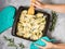 Female hands hold Italian pasta Conchiglioni Rigati stuffed with cheese and greens on concrete table.