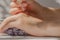 Female hands hold a pipette with lavender oil. Lavender oil dripping from a pipette on hands