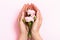 Female hands hold roses in the palms on a pink pastel background. Beauty and skin care concept