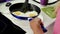 Female hands hold scrambled eggs in a pan, trying to separate food from dishes