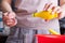 Female hands hold spoon and bottles of ready-made lemon juice in and pour it into the kneading dough from cottage cheese and flour