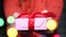 Female hands hold surprise gift box with red ribbon. Blurred garland in the foreground. Happy New Year, Birthday