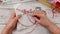 Female hands hold a tool for embroidering with ribbons - a hoop with a canvas and a needle with a thin ribbon