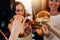 Female hands holding big tasty juicy hamburgers with blurred women in background