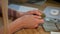 Female hands holding bitcoin. Crop view of hands of woman holding shiny metal bitcoin sitting at wooden desk with wad of