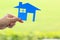 Female hands holding blue blank paper house on natural green background, Real estate and ownership property concept