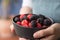 Female hands holding a bowl full of blackberries and raspberries