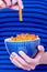 Female hands holding bowl with orange lentil fusilli pasta on a blue striped background. Diet and gluten free concept