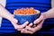 Female hands holding bowl with orange lentil fusilli pasta on a blue striped background. Diet and gluten free concept