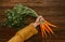 Female hands holding bunches of raw carrots