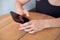 Female hands holding cell phone and a cup of coofee on the wooden table