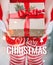 Female hands holding Christmas gift box with red ribbon and Merry Christmas and New Year typographical on shiny xmas background