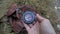 Female hands holding compass and looking for direction of North. Orientation in forest