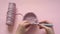 Female hands holding a crochet hook and pink color yarn on a pink background, knitting and crochet supplies