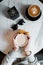 Female hands holding a cup with hot coffee in the cafe. Young woman is sitting in the morning indoor. Top view of the table