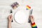 Female hands holding cutlery. Festive table setting with cutlery and gift with rainbow LGBT ribbon on a light wooden background