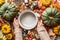 Female hands holding empty coking pan on table with many various colorful pumpkins and other autumn ingredients: nuts and spices.