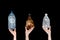 Female hands holding empty crushed plastic bottles isolated on black background. Recyclable waste. Recycling, reuse, garbage dispo