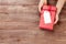 Female hands holding gift above wooden table