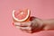 Female hands holding a glass of grapefruit juice on a pink background. Generative AI