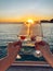 Female hands holding glasses of champagne on board the boat. Sunset sky and sea on the background. Making a celebratory toast with