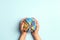 Female hands holding globe with LGBT rainbow ribbon on blue background. LGBT community