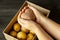 Female hands holding a heart-shaped ugly vegetable potato over a box filled with potatoes. square  ugly food