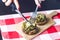 Female hands holding knife and fork and cutting meal. Mushrooms with cheese on a tablecloth. Appetizer. Food background