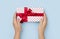 Female hands holding a lovely gift box on blue background