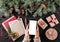 Female hands holding mobile phone. Christmas gift boxes with red decoration, Fir branches, pine cones on holiday background.