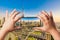 Female hands holding mobile smart phone and making photos of amazing skyline cityscape of Dubai with modern skyscrapers. Downtown