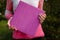 Female hands holding photobook or photoalbum with leather purple cover and wooden texture.