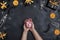 Female hands holding a piggy bank surrounded by halloween decorations on black background