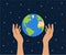 Female hands holding planet Earth on a blue starry space background. Earth day concept