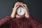 Female hands holding red alarm clock in front of face closeup