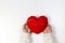 Female hands holding red polygonal heart on white background. Top view