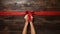 Female hands holding red ribbon bow on wooden background