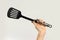 Female hands holding a spatula for frying. Isolated on gray back
