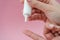 Female hands holding and squeezing tube of cream gel on pink background. Ð¡osmetic bottles for beauty or medicine products