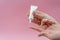 Female hands holding and squeezing tube of cream gel on pink background. Ð¡osmetic bottles for beauty or medicine products