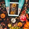 Female hands holding tablet pc with pumpkins photo on dark background with cup of hot chocolate and autumn arrangement of fall