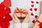 Female hands holding Valentines day gift above wooden table with red hearts. Top view. Xmas gift wrapping