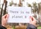 Female hands holding white paper sheet with text THERE IS NO PLANET B outdoors. Nature background. Protester activist