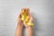 Female hands holding yellow ribbon on light background. Cancer concept