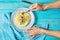 Female hands holds a fork. Pasta with chanterelle mushroom and ingredients on blue wooden background.