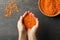 Female hands holds red legumes over a dark background with bowl of legumes